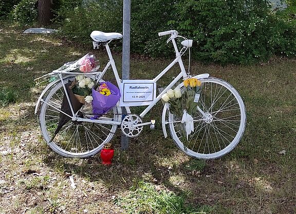 Mit Blumen geschmücktes weißes Fahrrad am Ortsschild von Neutraubling